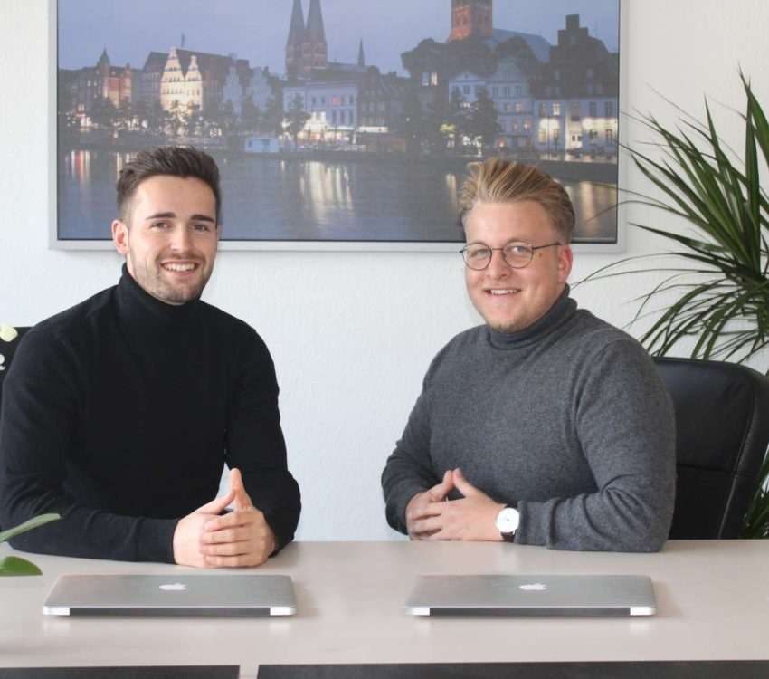Ein Teambild der Energieberatung Hamburg Archisell. Zu sehen sind die beiden Gründer Kevin Sell und Jan-Ole Urbanski am Tisch hinter Ihren Laptops.